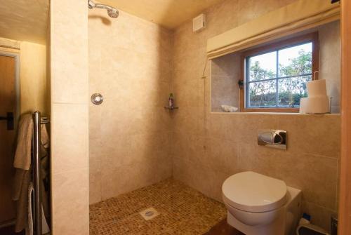 La salle de bains est pourvue de toilettes, d'une fenêtre et d'une douche. dans l'établissement Mill Cottage set beside a Mill pond in a 70 acre Nature Reserve Bliss, à Assington