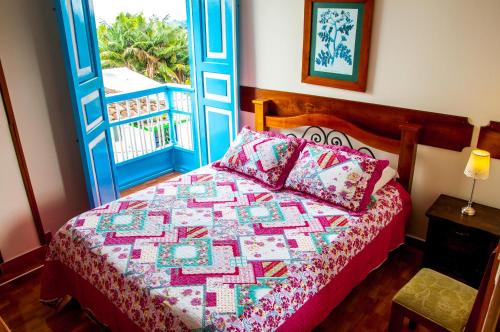 een slaapkamer met een bed met een quilt bij Hotel Camino Nacional Salento in Salento