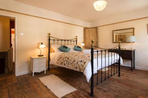 - une chambre avec un lit noir et un miroir dans l'établissement Romney, a cosy Victorian cottage in a picturesque Suffolk village, à Cavendish