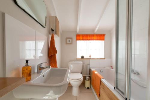 a bathroom with a tub and a toilet and a sink at Romney, a cosy Victorian cottage in a picturesque Suffolk village in Cavendish