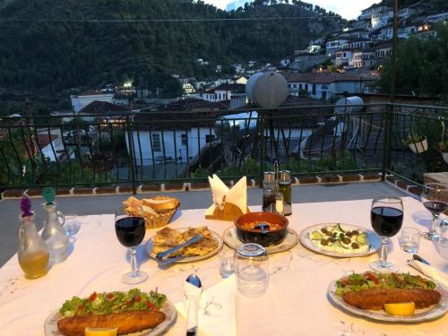 een tafel met borden en glazen wijn bij Guest House Baba Lluka in Berat