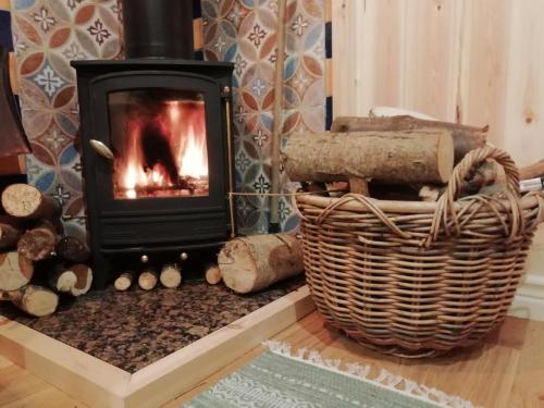 a fireplace with a fire burns in a room at Sapphire forest garden shepherd’s hut in Church Stretton