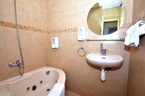 uma casa de banho com um lavatório, uma banheira e um espelho. em Gan Hakramim Country Lodging em Kramim