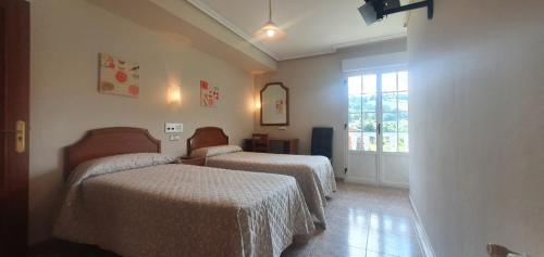 a hotel room with two beds and a window at Apartamentos centro Asturias, a 10 minutos de Oviedo in Mieres