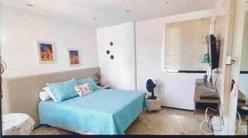 1 dormitorio con 1 cama azul y TV en Alugo suíte em lindo apto beira-mar na P. Verde., en Maceió