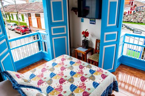 a room with blue doors and a quilt on a bed at Hotel Camino Nacional Salento in Salento