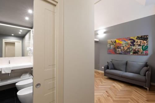 a bathroom with a sink and a couch in it at Palazzo Liberati Apartments in Parma