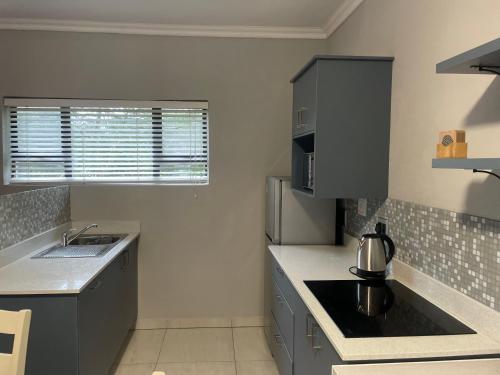 a kitchen with gray cabinets and a sink and a window at Q's Palace in Kloof