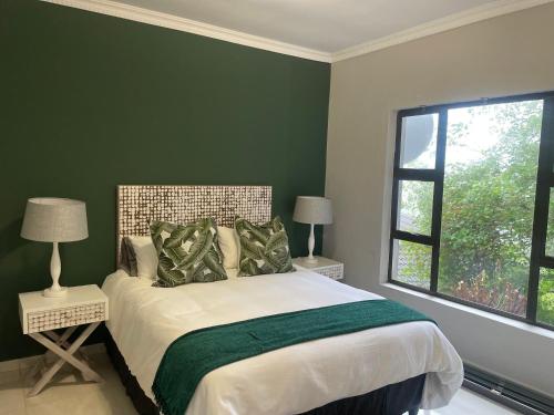 Un dormitorio con una cama con paredes verdes y una ventana en Q's Palace, en Kloof