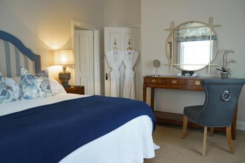 Schlafzimmer mit einem Bett, einem Schreibtisch und einem Spiegel in der Unterkunft Maplewood Cottage, Wynyard Hall 