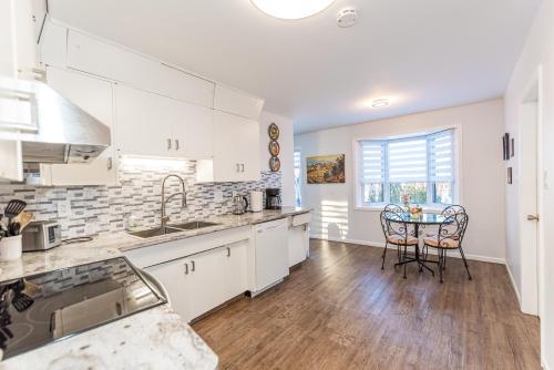 a kitchen with white cabinets and a table with chairs at Southgate 5 Bedroom Vacation Home with Double Garage in Edmonton