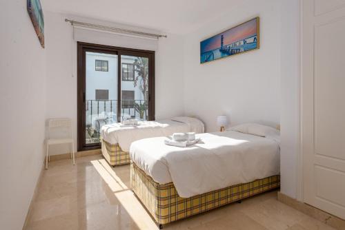 two beds in a room with a window at 2113-Beautiful 2 beds apt with seaview in La Alcaidesa