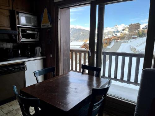 - une table dans la cuisine avec vue sur une montagne enneigée dans l'établissement La Bartavelle - Petit duplex avec balcon à proximité des pistes, à Courchevel