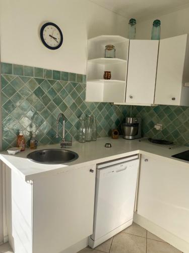 une cuisine avec un évier et une horloge murale dans l'établissement La Canopé, à Aubais