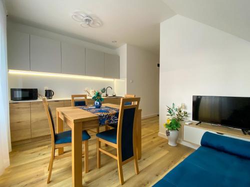 uma cozinha e sala de jantar com uma mesa e um sofá azul em Apartamenty Bianka em Wisla