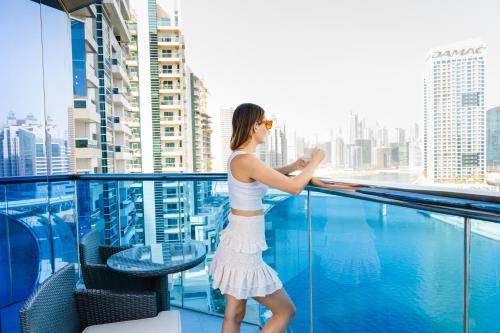 Hyde Hotel Dubai في دبي: امرأة تقف على شرفة تطل على المدينة