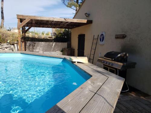 une piscine bleue avec une terrasse en bois à côté d'une maison dans l'établissement Villa Les Roches Blanches Le Ptit du Sud, à Martigues