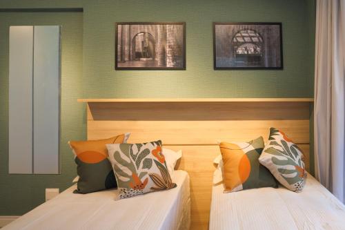 2 camas en una habitación con paredes verdes en XBase Studio Parque Augusta-Higienópolis Mackenzie en São Paulo