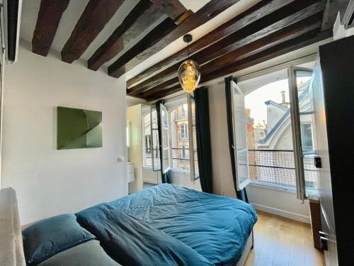 une chambre avec un lit et une grande fenêtre dans l'établissement Designer Apartment Tour Saint-Jacques - 1BR 4P, à Paris