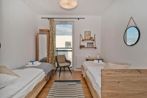 twee bedden in een kamer met een spiegel en een stoel bij BlueApart Apartamenty Hotelowe Nexo II in Puck
