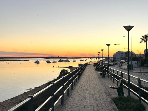 a pier with boats in the water at sunset at Golden Club- Eyes on Sea in Cabanas de Tavira