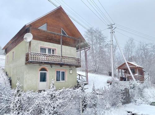 a house with a balcony on top of it in the snow at Карпатський будинок in Izki