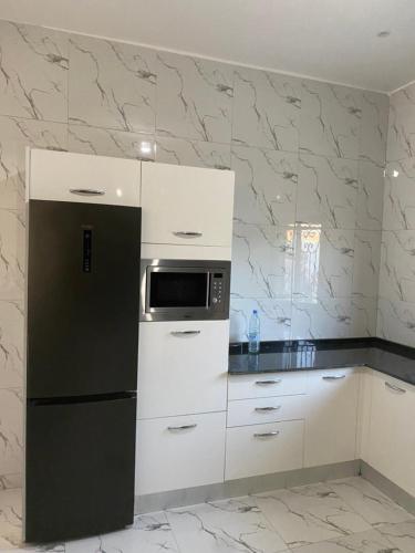 a kitchen with a black refrigerator and white cabinets at La Baraka, extravagant villa for 8 with pool in Saly in Gandigal