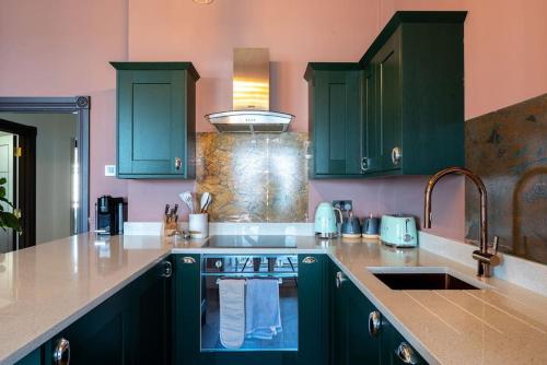 a kitchen with green cabinets and a sink at Stylish Beachfront Apartment, Sweeping Ocean Views and Luxury Touches in Herne Bay