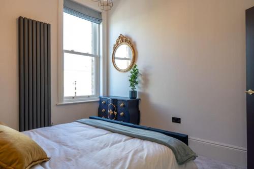 1 dormitorio con cama con espejo y ventana en Stylish Beachfront Apartment, Sweeping Ocean Views and Luxury Touches, en Herne Bay