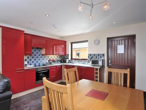 a kitchen with red cabinets and a wooden table at Composers at Woodlands in East Ord