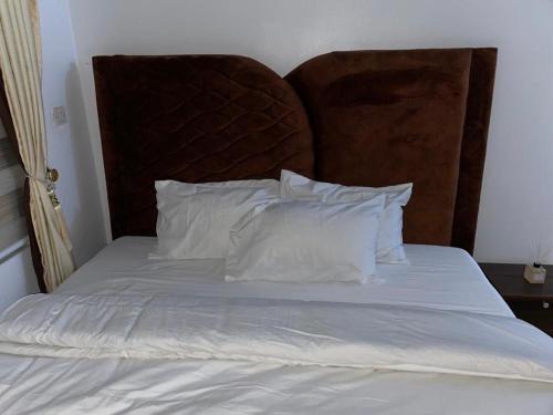 a bed with white pillows and a brown headboard at Exquisite 2-Bedroom Apt in Oniru in Lagos