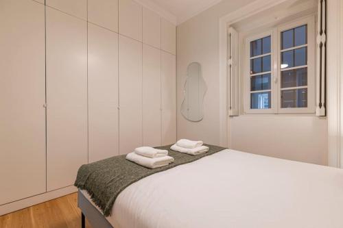 a white bedroom with a bed with towels on it at Secret Garden by Innkeeper in Lisbon