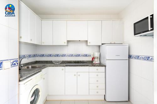 a white kitchen with a sink and a refrigerator at Apartamentos EL Rocio Casa Azahar in Alcossebre