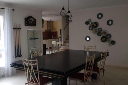 une salle à manger avec une table et des chaises noires dans l'établissement Villa avec Piscine a St Marie la Mer, à Sainte-Marie-la-Mer