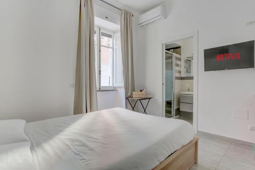 ein weißes Schlafzimmer mit einem Bett und einem Spiegel in der Unterkunft Santi Quattro Apartment & Rooms - Colosseo in Rom