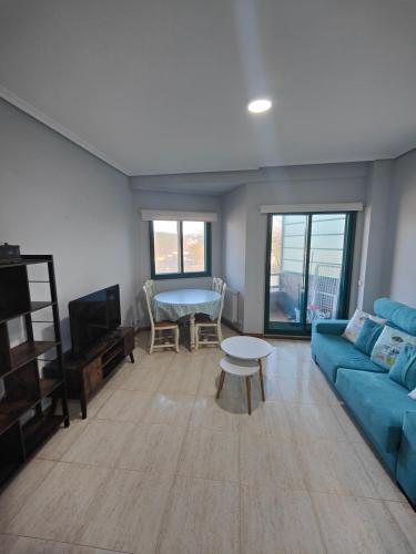 a living room with a blue couch and a table at Apartamento Samil Primera Línea de Playa 2F in Vigo