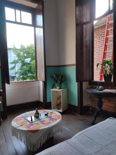 salon ze stołem i 2 oknami w obiekcie Casarão artístico em Santa Teresa w mieście Rio de Janeiro
