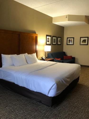 a hotel room with a large bed and a couch at Wingate by Wyndham Grove City in Grove City