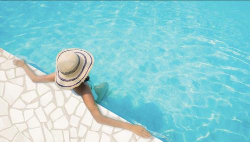 kobieta w kapeluszu leżąca w basenie w obiekcie MiaBella Resort w mieście Drage
