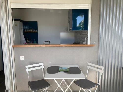 a kitchen with a table and two chairs and a counter at Bleu Cannelle et Petimo in Le Diamant