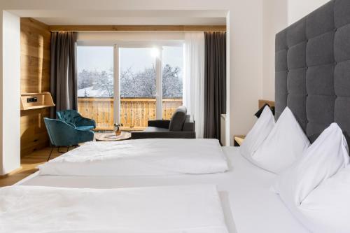 Un dormitorio con una gran cama blanca y una ventana en Hotel Moarhof, en Lienz