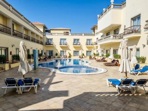 einen Pool im Innenhof eines Hotels mit Stühlen und Sonnenschirmen in der Unterkunft IL Mercato Hotel & Spa in Sharm El Sheikh