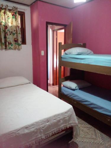 2 stapelbedden in een kamer met paarse muren bij Kalena Suítes in Lençóis