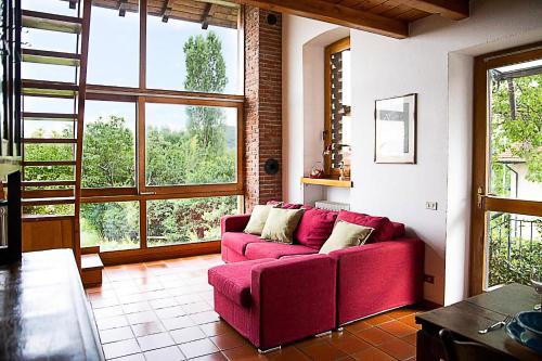 uma sala de estar com um sofá vermelho e janelas grandes em Il Gelsomino - Terrace Country House em Pisano