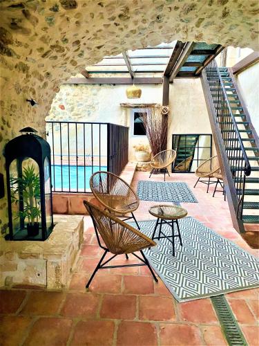 d'une terrasse avec des chaises et des tables sur un sol en briques. dans l'établissement GITE DE GROUPE 9ch ou 3 GITES Indépendants de 3ch - PATIO et PISCINE INTERIEURE CHAUFFEE TOUTE L'ANNEE, à Vallon-Pont-dʼArc