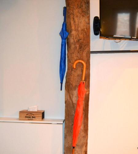 a red umbrella hanging on a wall next to a refrigerator at Un jour d'été à Albi - Centre Unesco - 200 m Cathédrale - Parking - Animaux acceptés in Albi