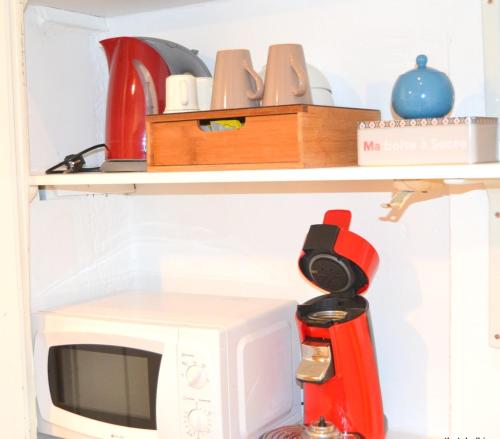 a kitchen shelf with a microwave and a red appliance at Un jour d'été à Albi - Centre Unesco - 200 m Cathédrale - Parking - Animaux acceptés in Albi