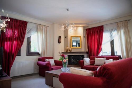 una sala de estar con muebles rojos y cortinas rojas. en Villa Valentina, en Kala Nera