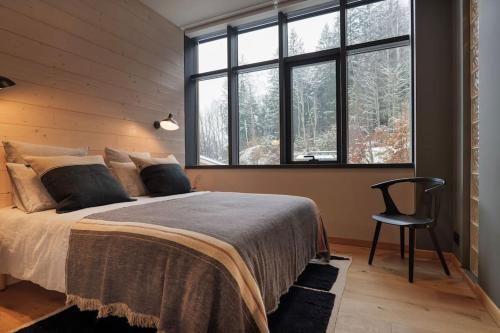 une chambre avec un lit, une chaise et des fenêtres dans l'établissement Appartement Rooftop Chamonix, à Chamonix-Mont-Blanc