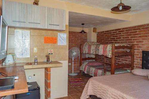 Habitación con 1 dormitorio con 1 cama y cocina en Posada Tinktinkie en Santa Rosa de Calamuchita